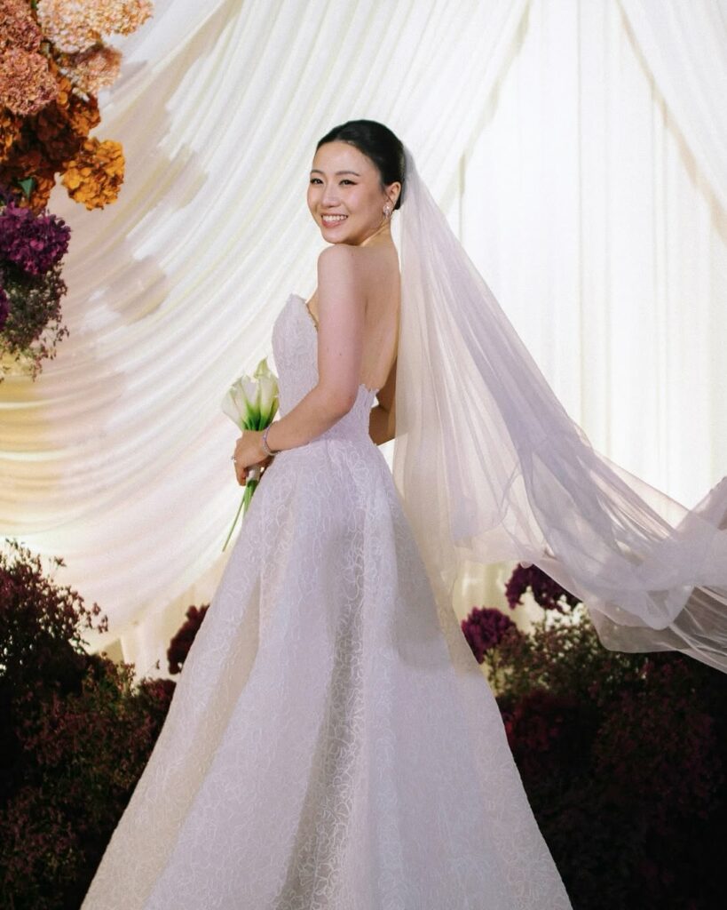 Katya Ruiz in strapless gown, veil, white bouquet.