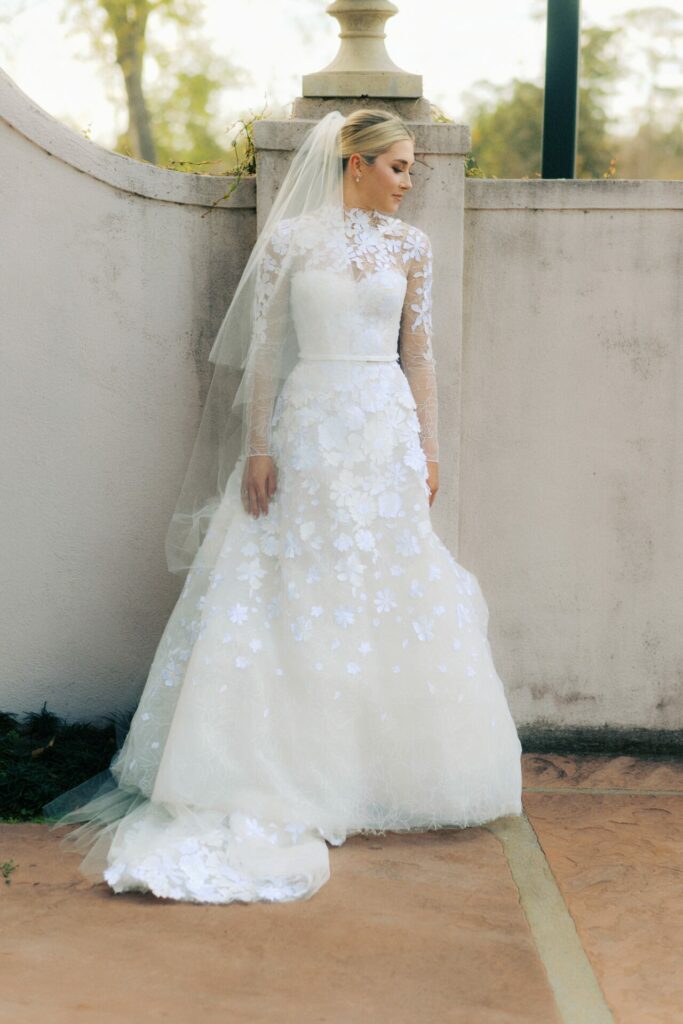 Katya Ruiz in long-sleeve lace gown and veil outdoors.