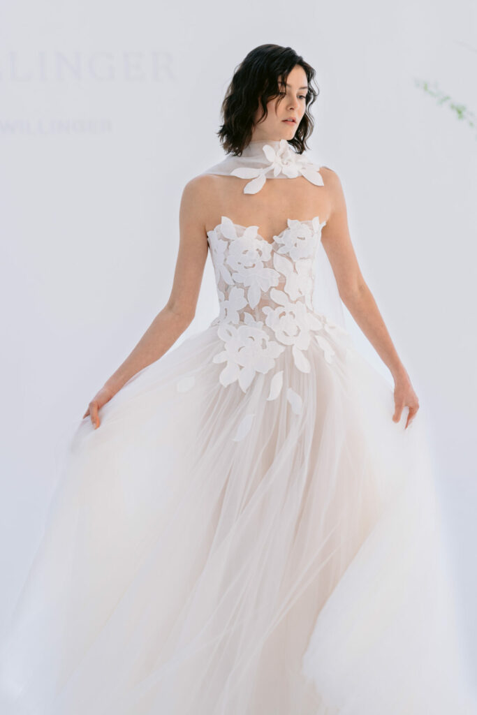 Bride in sheer white gown with floral appliqués.