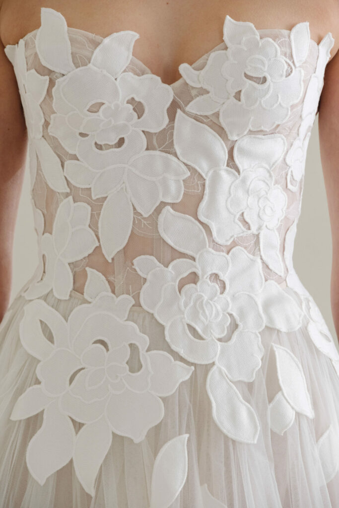 Strapless white dress with sheer, floral appliqués.