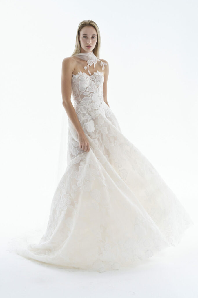 Woman in strapless white floral gown with neckpiece.