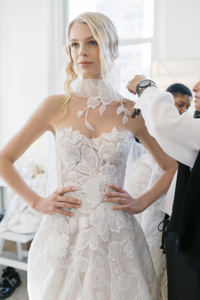 Woman in white lace gown, scarf adjusted, serene.