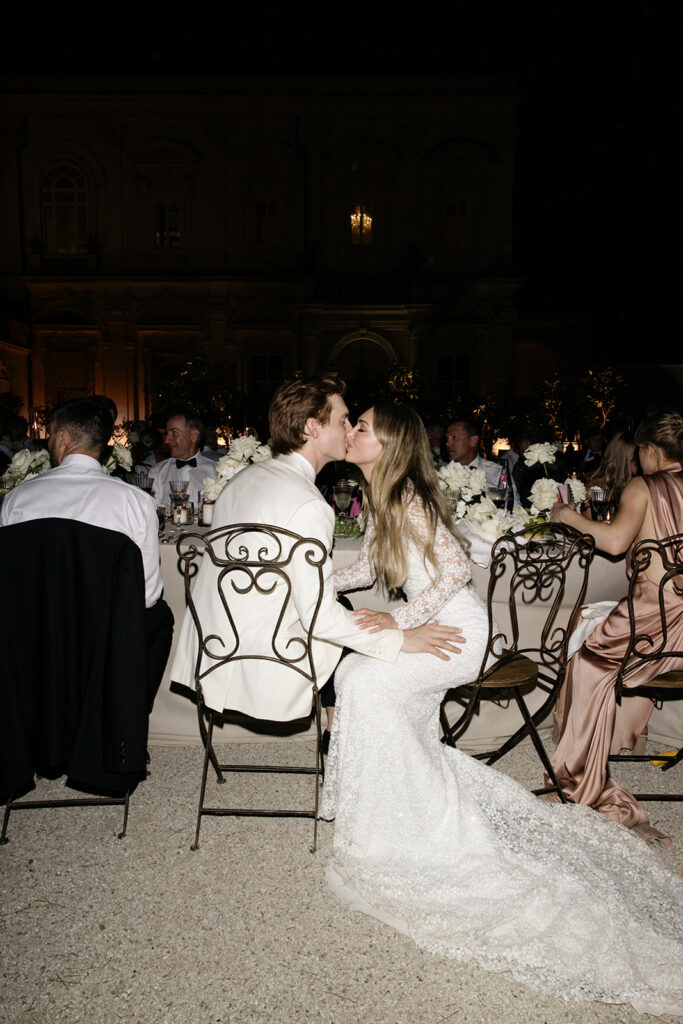 Bride and groom kiss at outdoor night wedding reception.