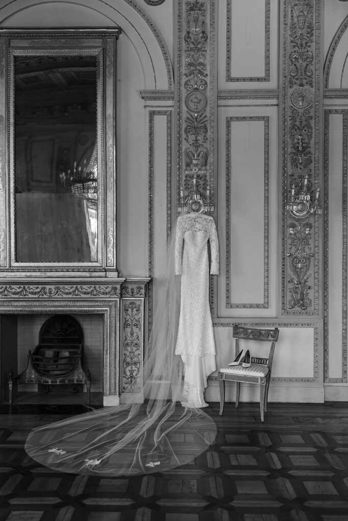 Bridal gown and veil hang in elegant, ornate room.