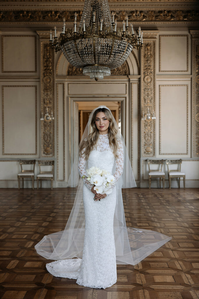 Bride in lacy Mira Zwillinger gown, ornate room.