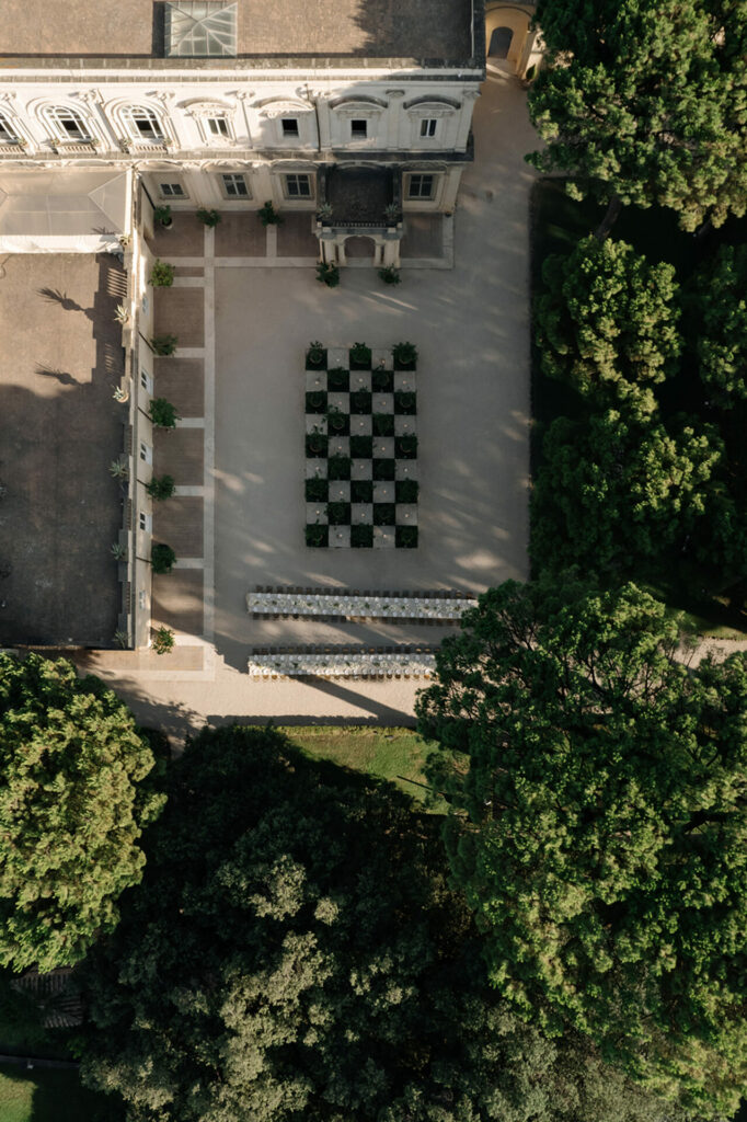 Courtyard with checkerboard pattern, trees, and classical building.