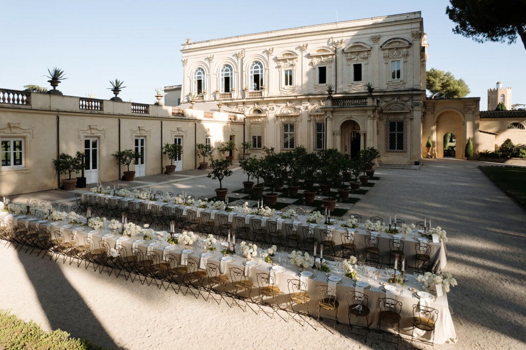 Elegant outdoor banquet tables with florals by historic building.