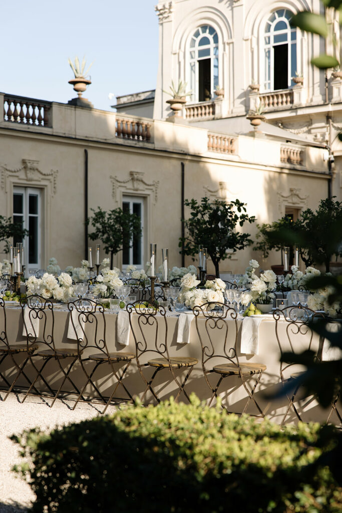 Chic outdoor table with flowers, candles, glassware, greenery.