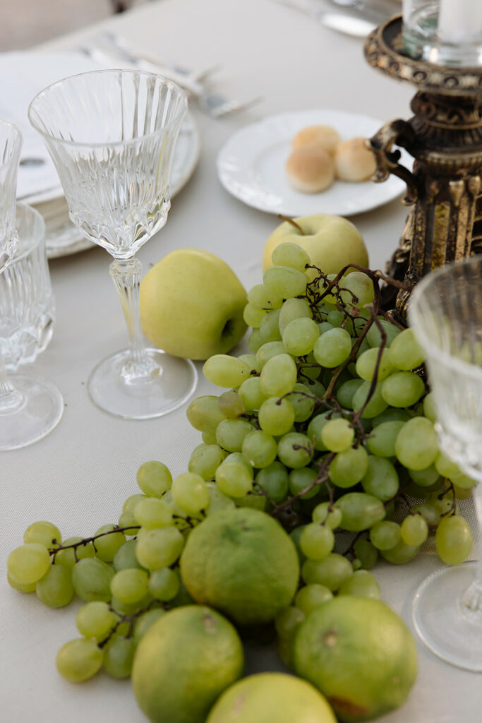 Elegant table with crystal glasses, fruit centerpiece, bridal vibe.