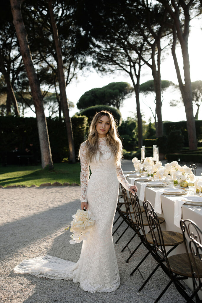 Katya Ruiz in lace gown outdoors by flower table.