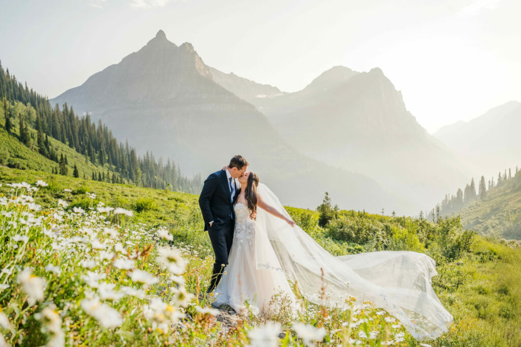 Bride and groom kiss in wildflower mountain meadow.
