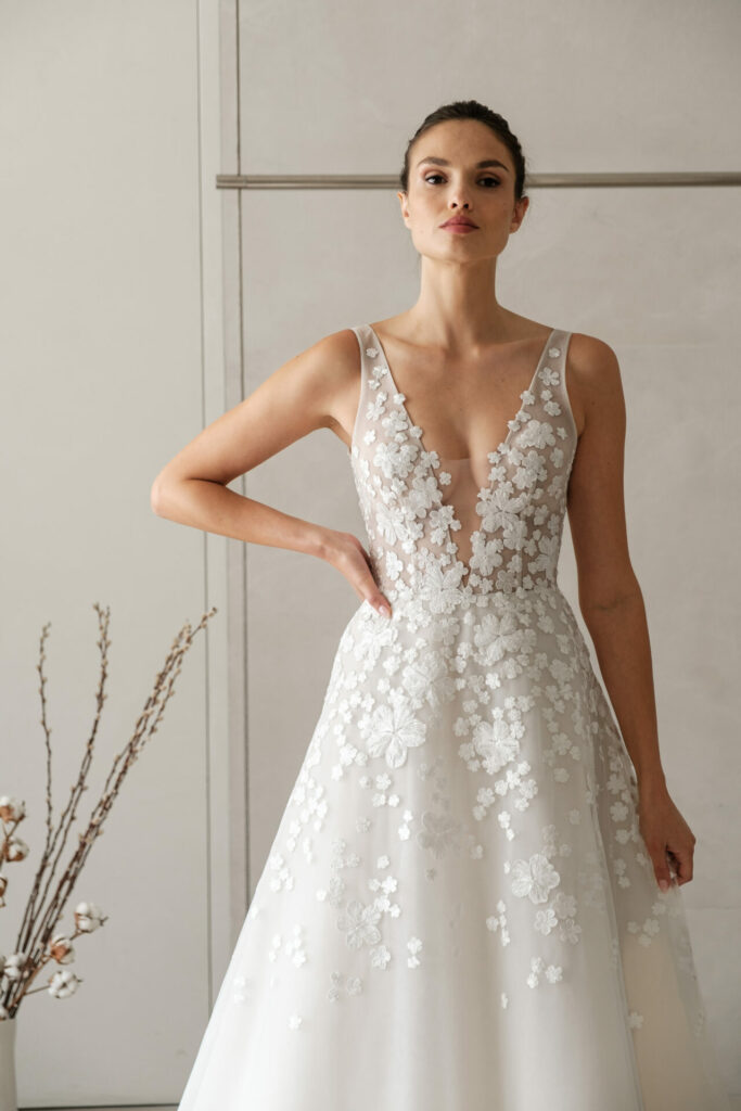 Woman in white lace wedding dress, vase nearby.