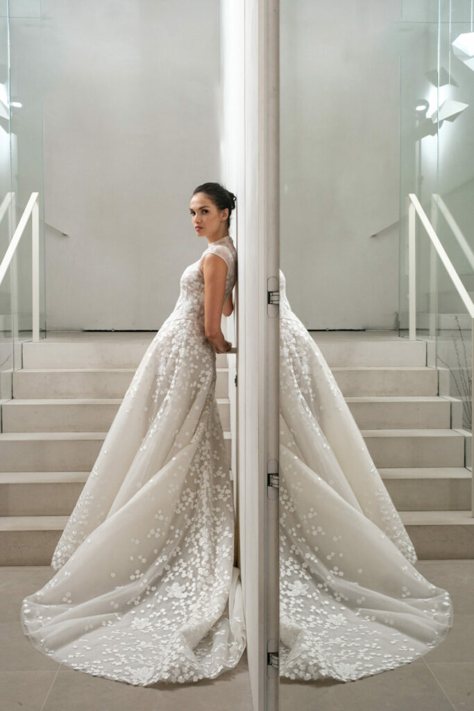 Bride in floral wedding dress reflected by mirrored wall.