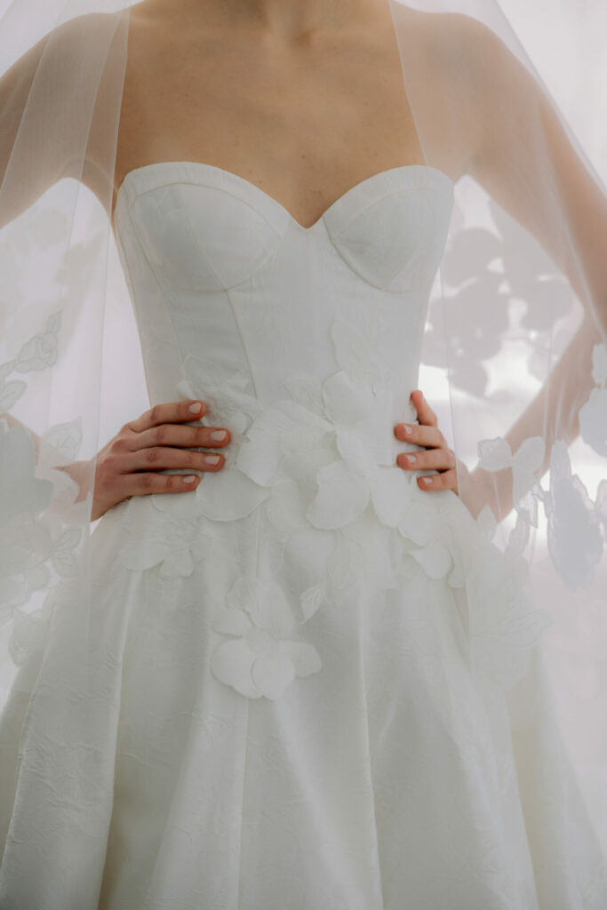 Bride in strapless floral gown and sheer floral veil.
