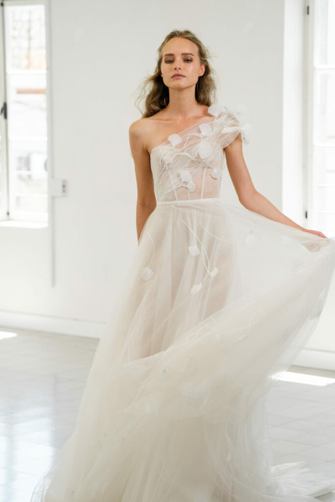 Bride in off-shoulder tulle gown, soft indoor light.