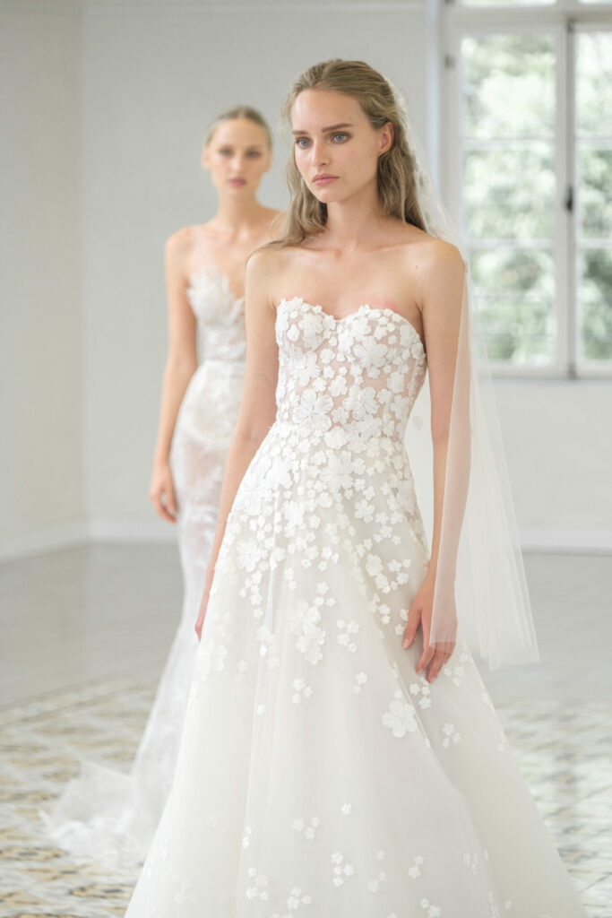 Ness & Nessia in white bridal gowns indoors.