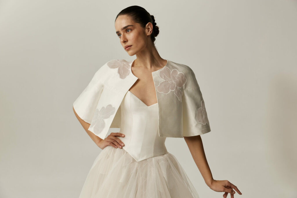 Woman in modern white tulle gown and floral cape.