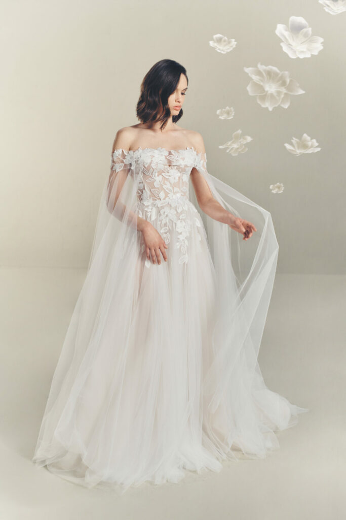 Woman in sheer floral gown, dreamy white blossoms.