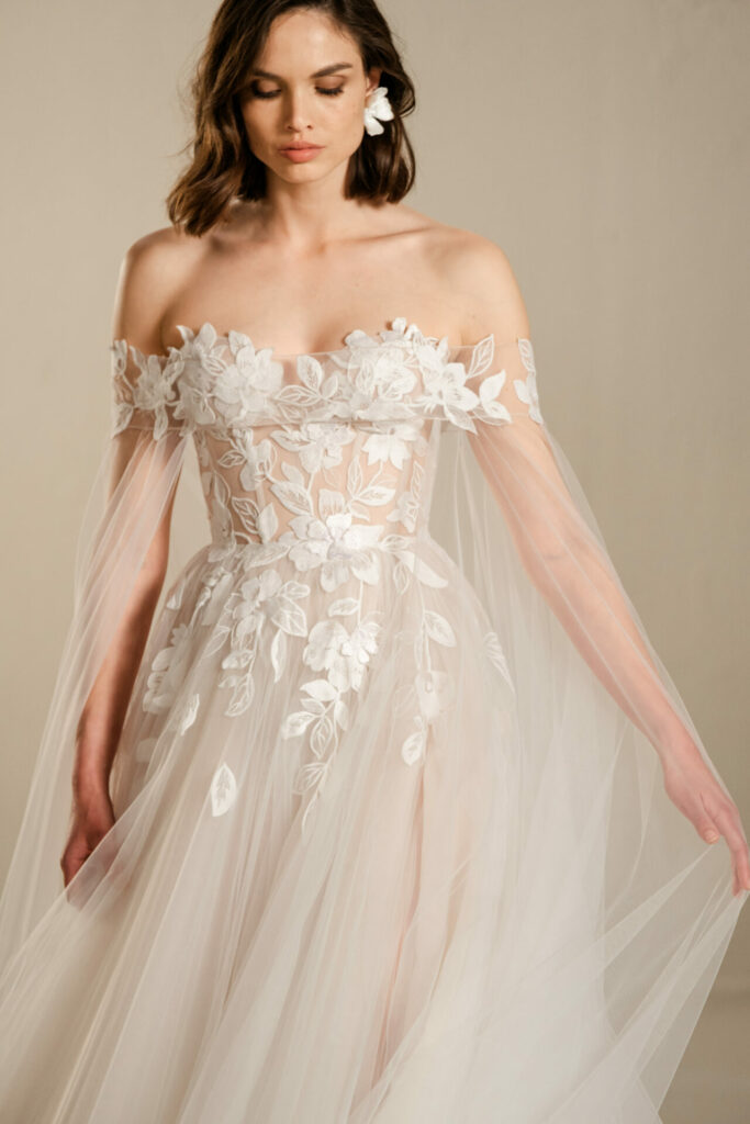 Woman in sheer off-shoulder white floral bridal gown.