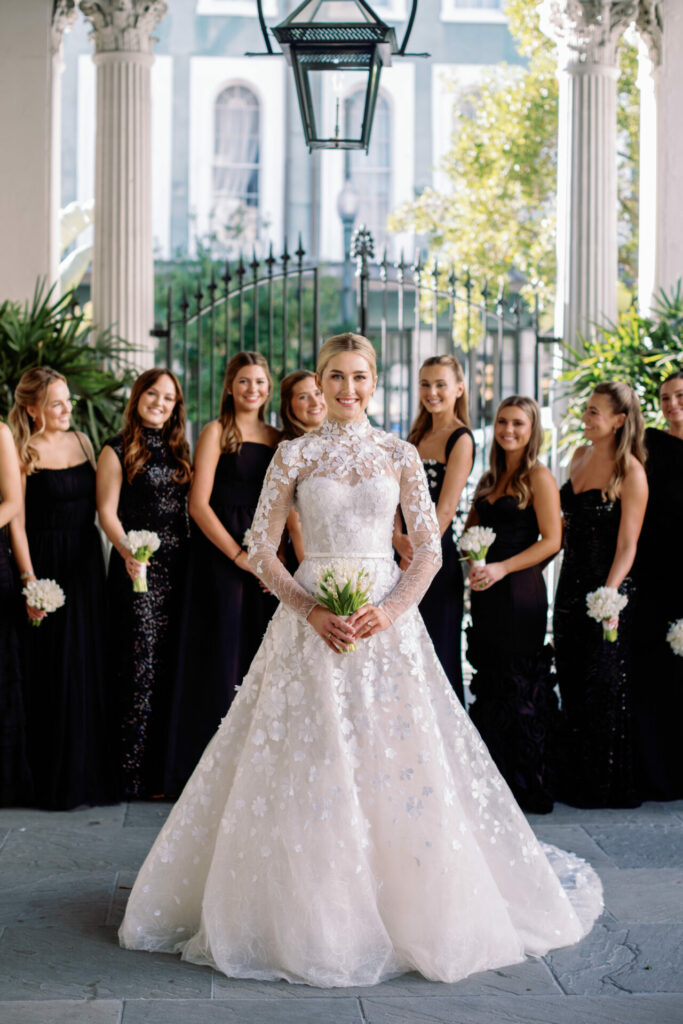 Bride in lace gown with bridesmaids in black dresses.