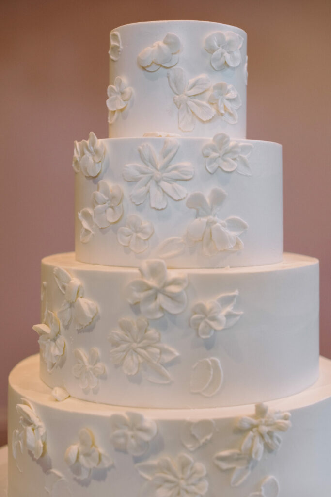 Elegant four-tier white cake with textured white flowers.