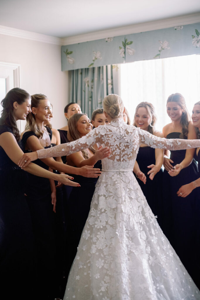 Bride in luxury gown surrounded by smiling bridesmaids.