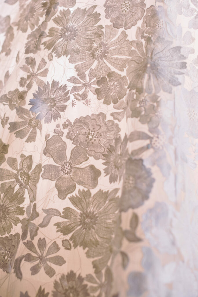 Sheer fabric with intricate floral lace, softly backlit.