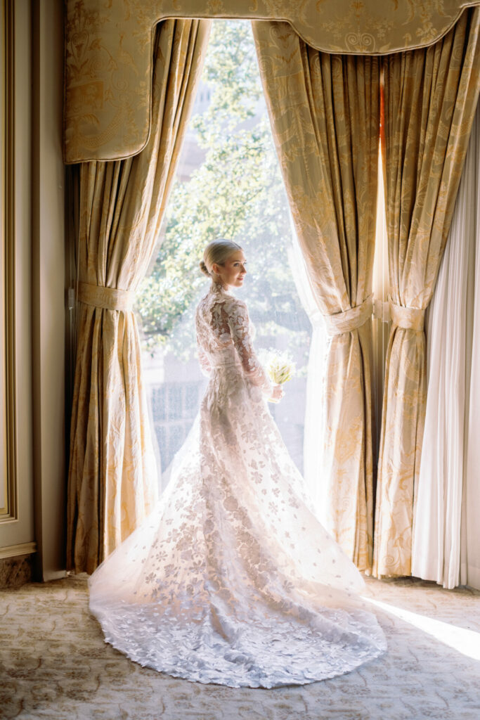 Katya Ruiz in luxury gown, bouquet in hand, smiling.