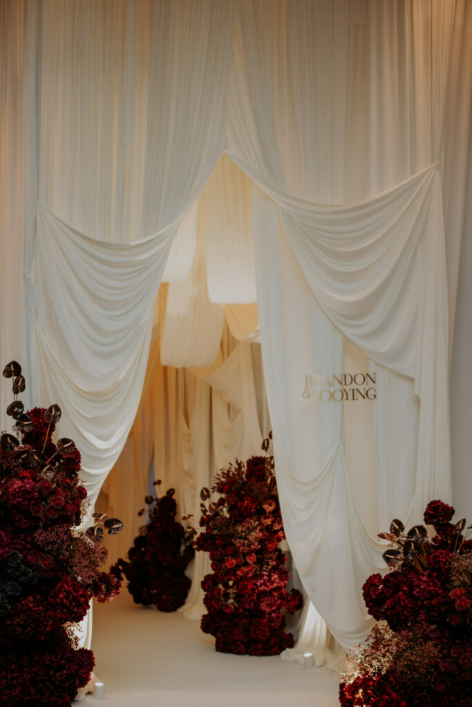 Elegant wedding entrance, red roses, drapes, Brandon & Sooying.