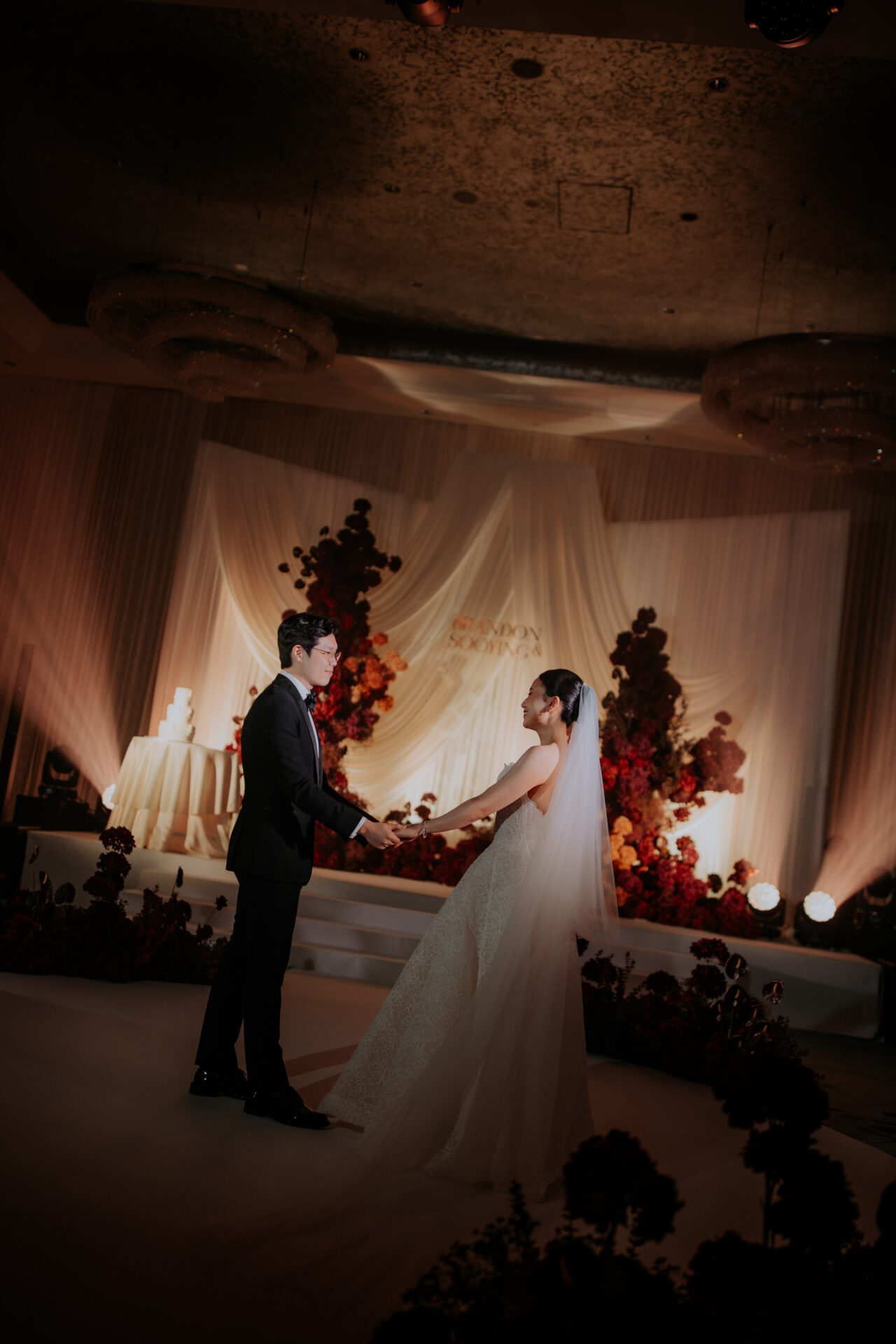 Katya Ruiz and groom hold hands on elegant wedding stage.