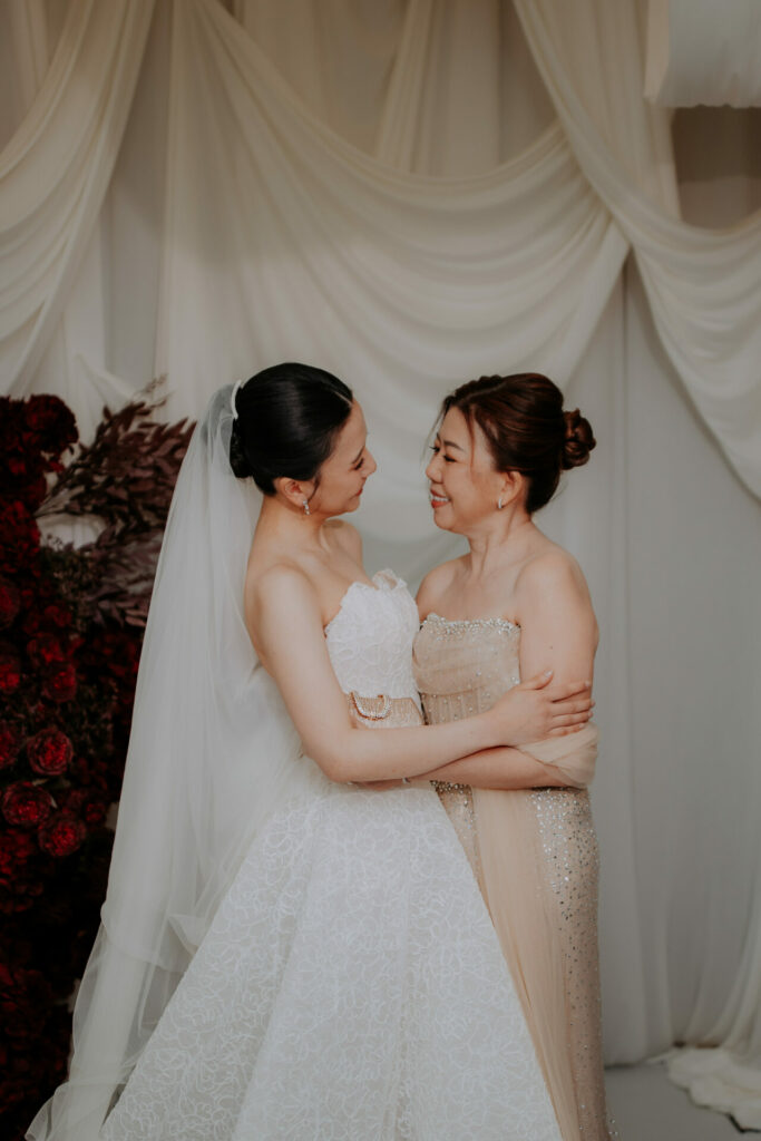 Katya Ruiz hugs partner in luxe Mira Zwillinger gown.