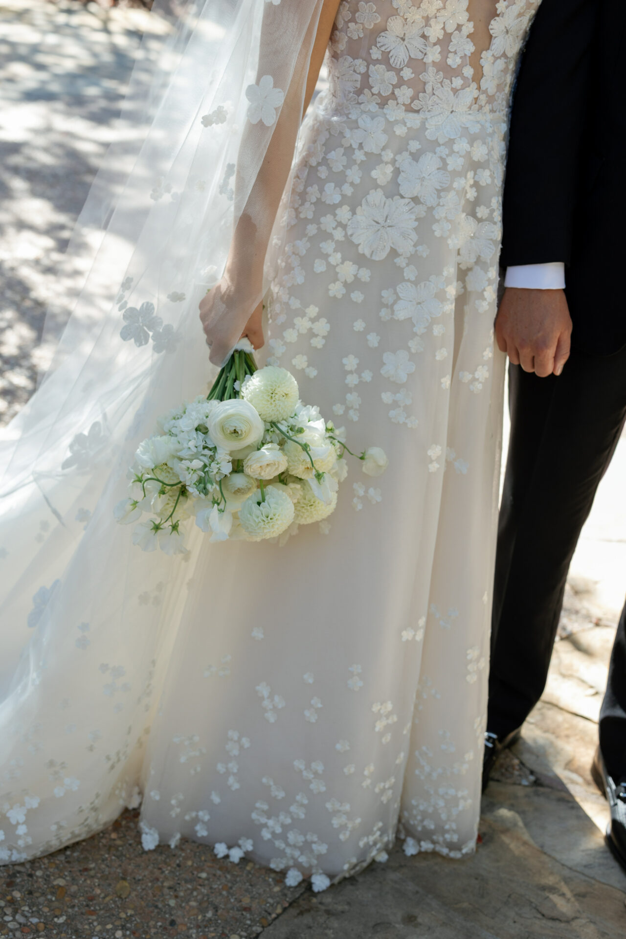 Bride and groom torso, lace dress, white bouquet.