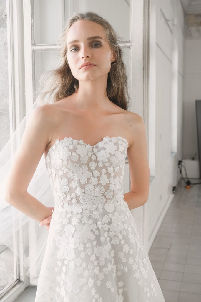Woman in strapless floral lace wedding dress indoors.