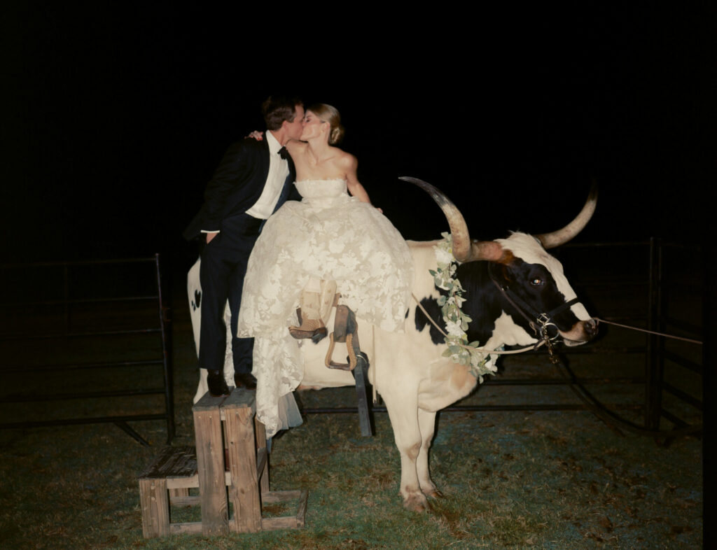 Bride Katya Ruiz kisses groom on flower-adorned steer.