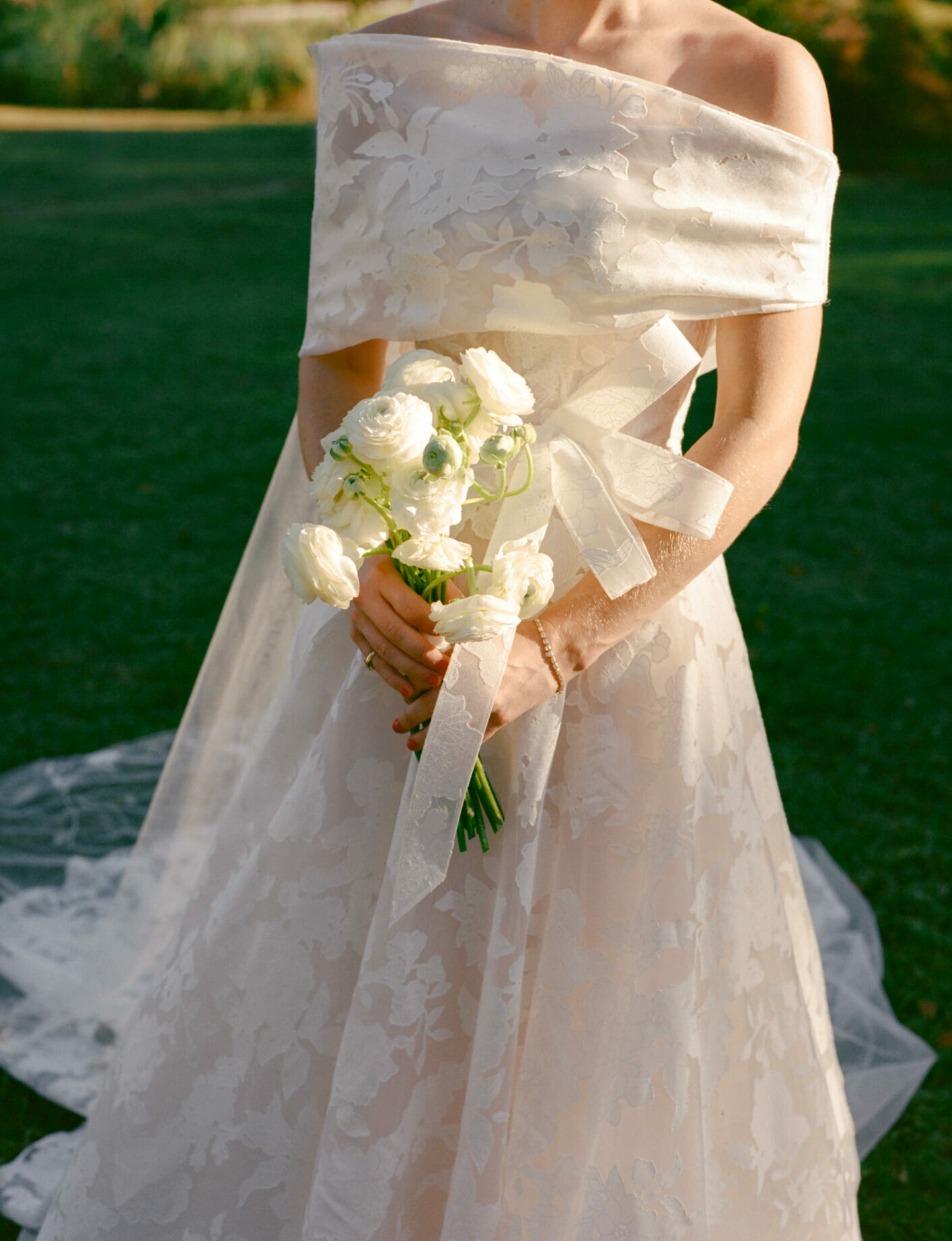 Katya Ruiz in floral Mira Zwillinger gown, sunlit, holding white bouquet.