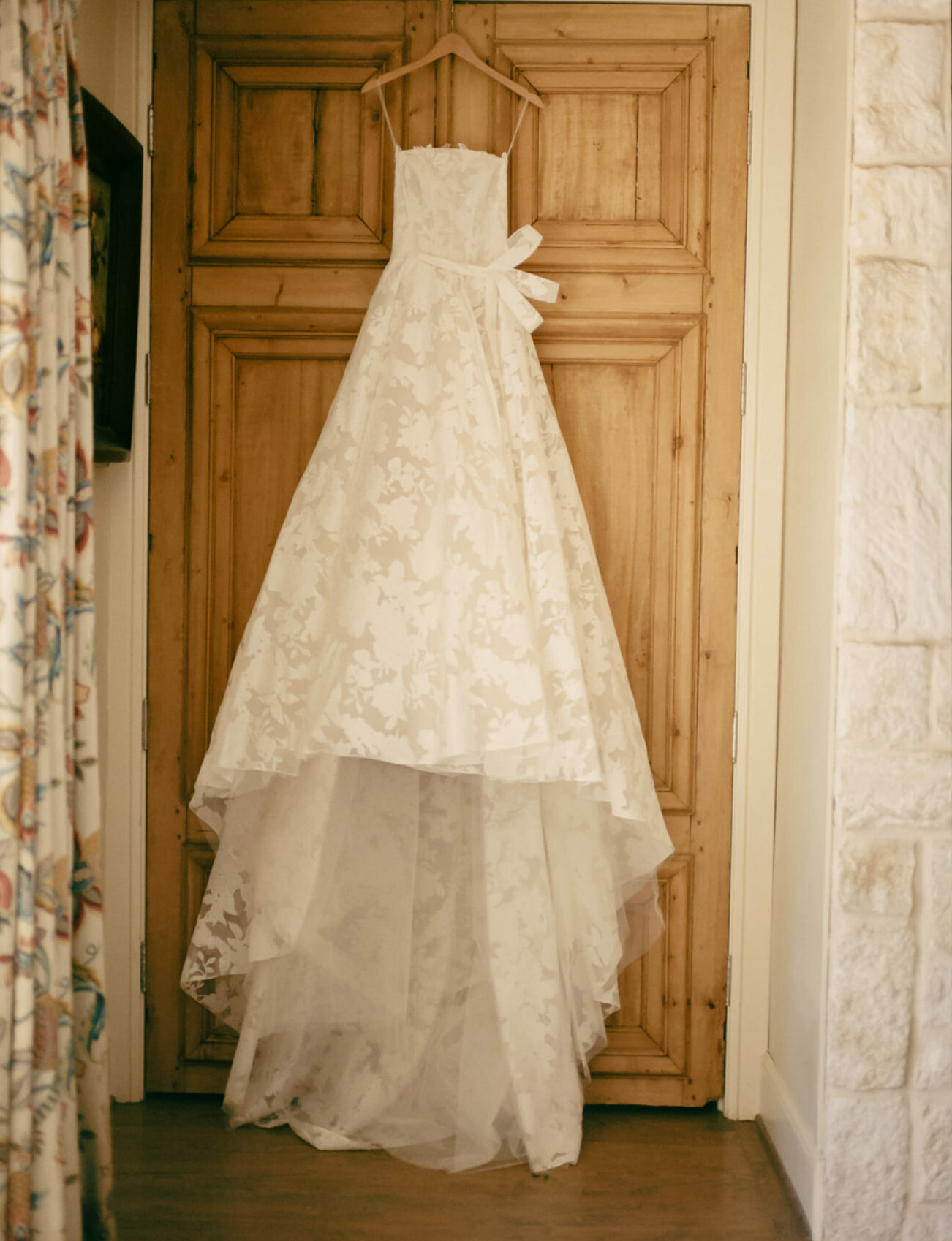 White high-low floral wedding dress on wooden door.