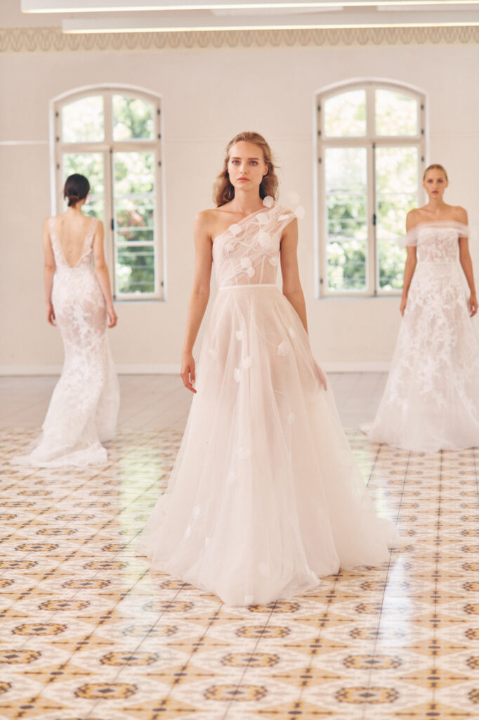 Three brides in white Mira Zwillinger dresses, sunlight.