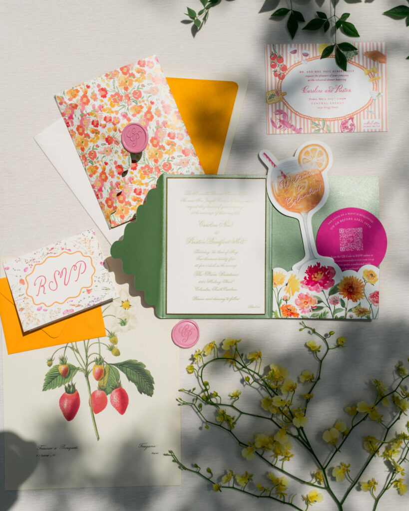 Wedding stationery flat lay with florals, strawberries, couture nod.