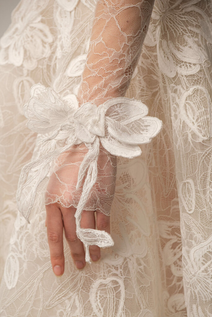 Hand in sheer floral lace sleeve, white flower wrist.