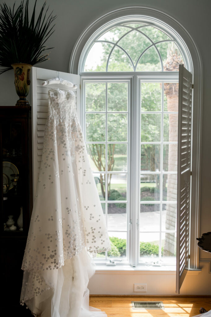 Floral Mira Zwillinger gown hangs by arched window.