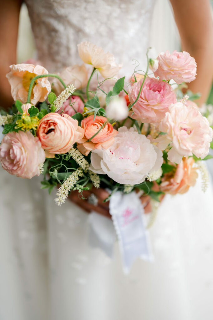 Katya Ruiz in white lace gown, pastel bouquet.