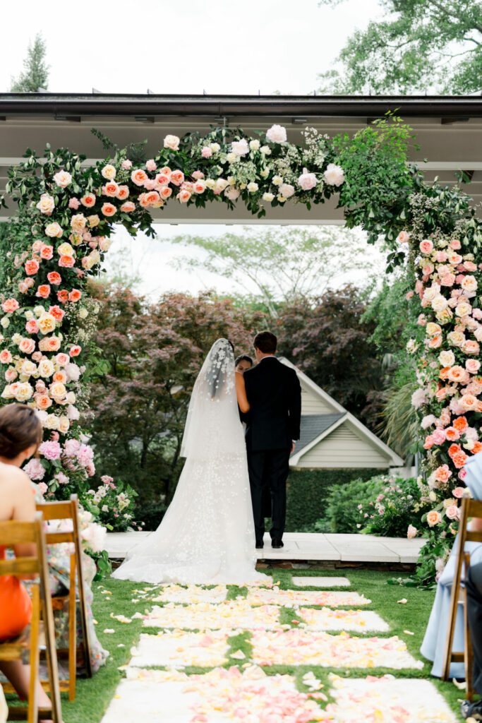 Bride Katya Ruiz and groom under floral arch outdoors.