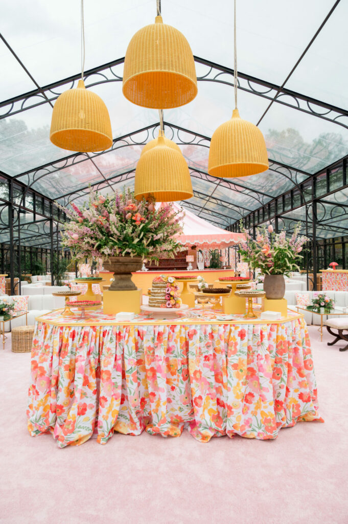 Bright dessert table with flowers, pastries, and wicker lights.