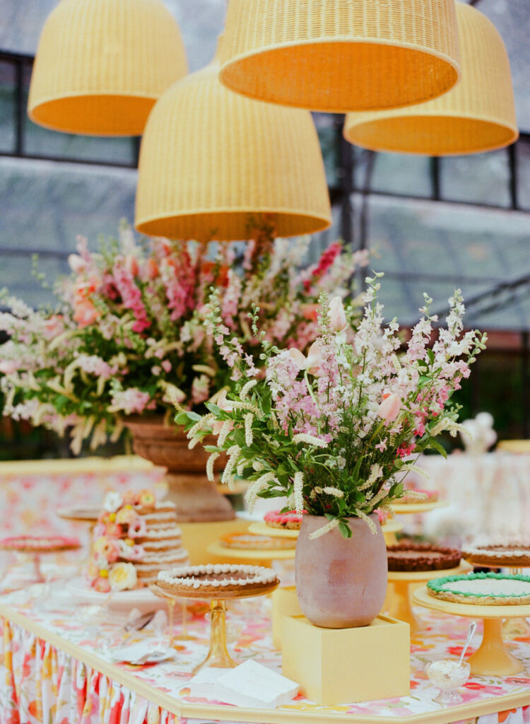 Dessert table with cakes, flowers, and basket lights.