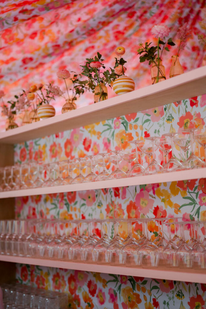 Bright, floral wall shelves with glassware and flowers.