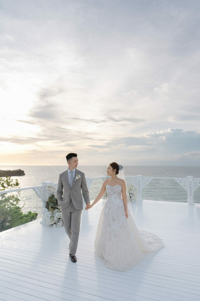 Bride and groom walk hand in hand at sunset.