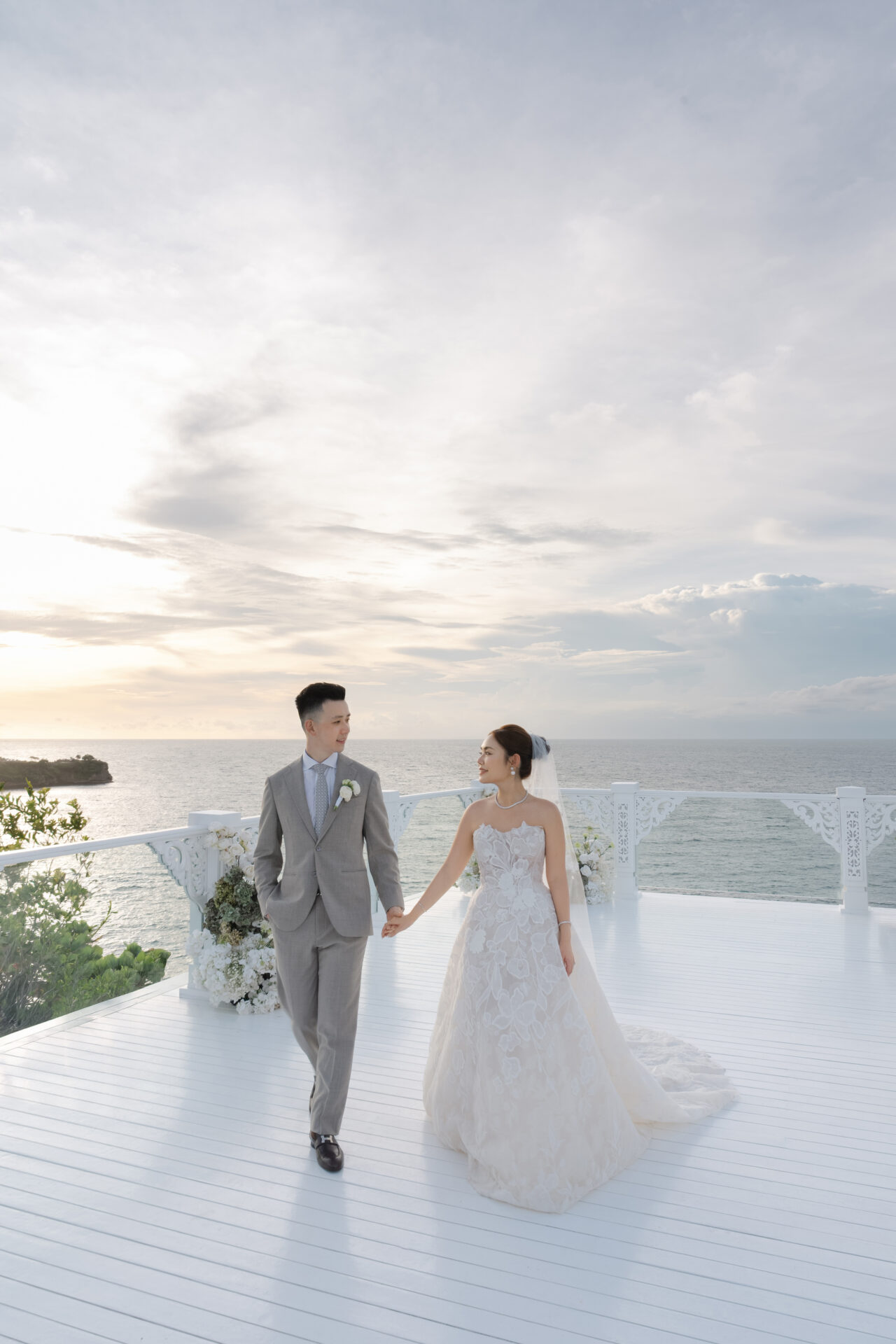 Bride and groom walk hand in hand at sunset.