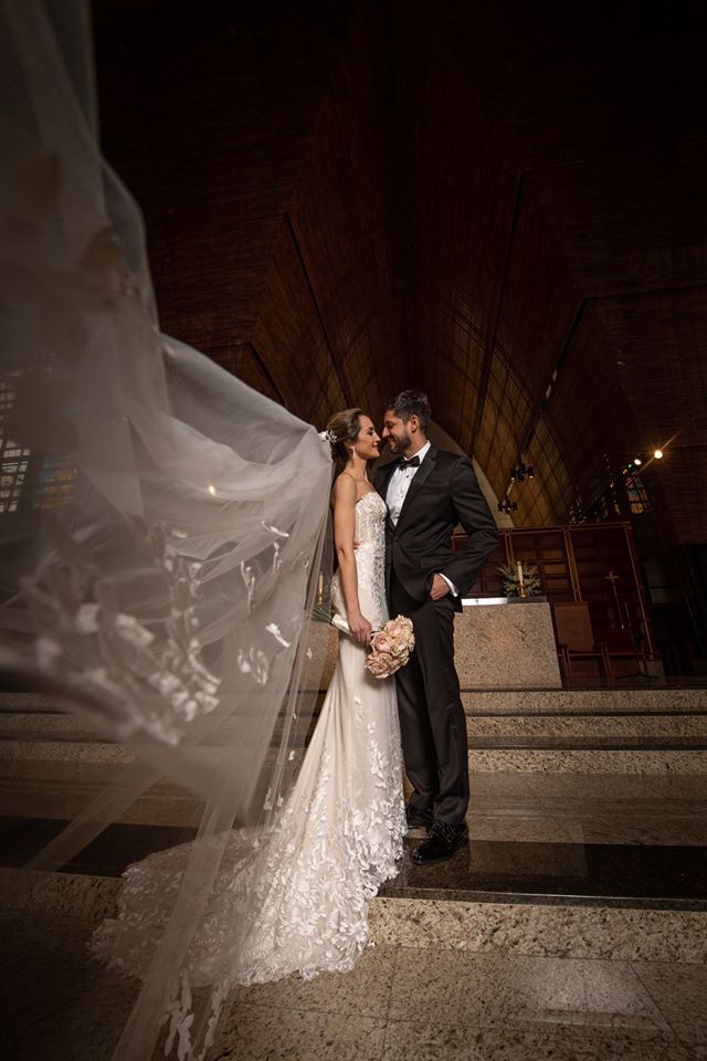 Bride and groom embrace on marble steps, elegant setting.