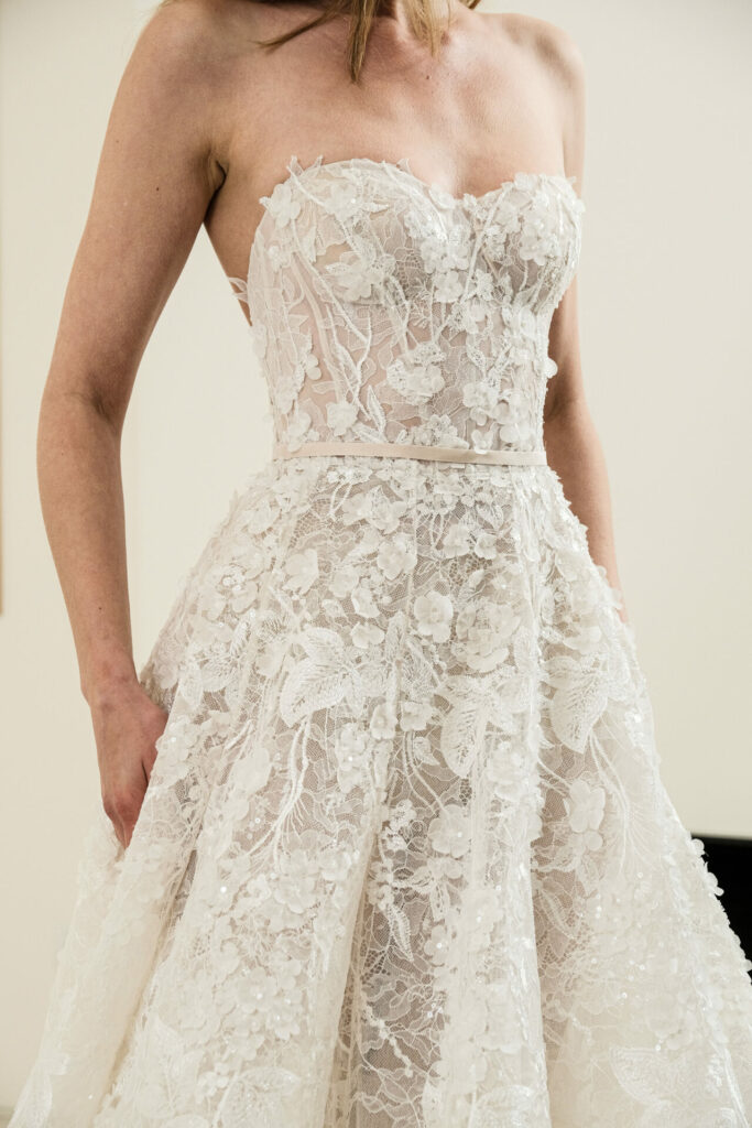 Woman in strapless ivory lace wedding gown indoors.
