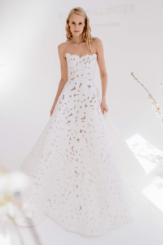 Blonde woman in strapless floral gown, smiling.